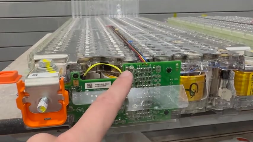 Close-up of a Tesla Model S BMB with a finger pointing at corroded capacitors C26 and C27