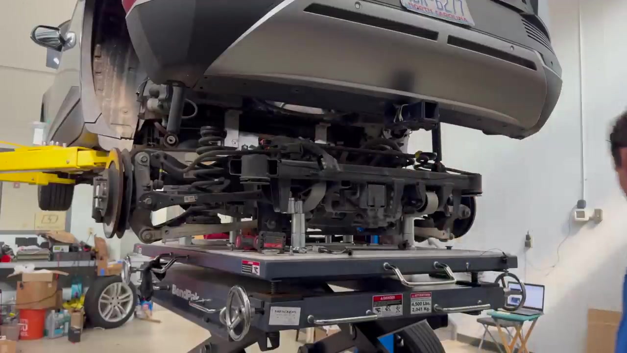 IONIQ 5 on a two-post lift with the rear subframe and drive unit sitting on a lift table