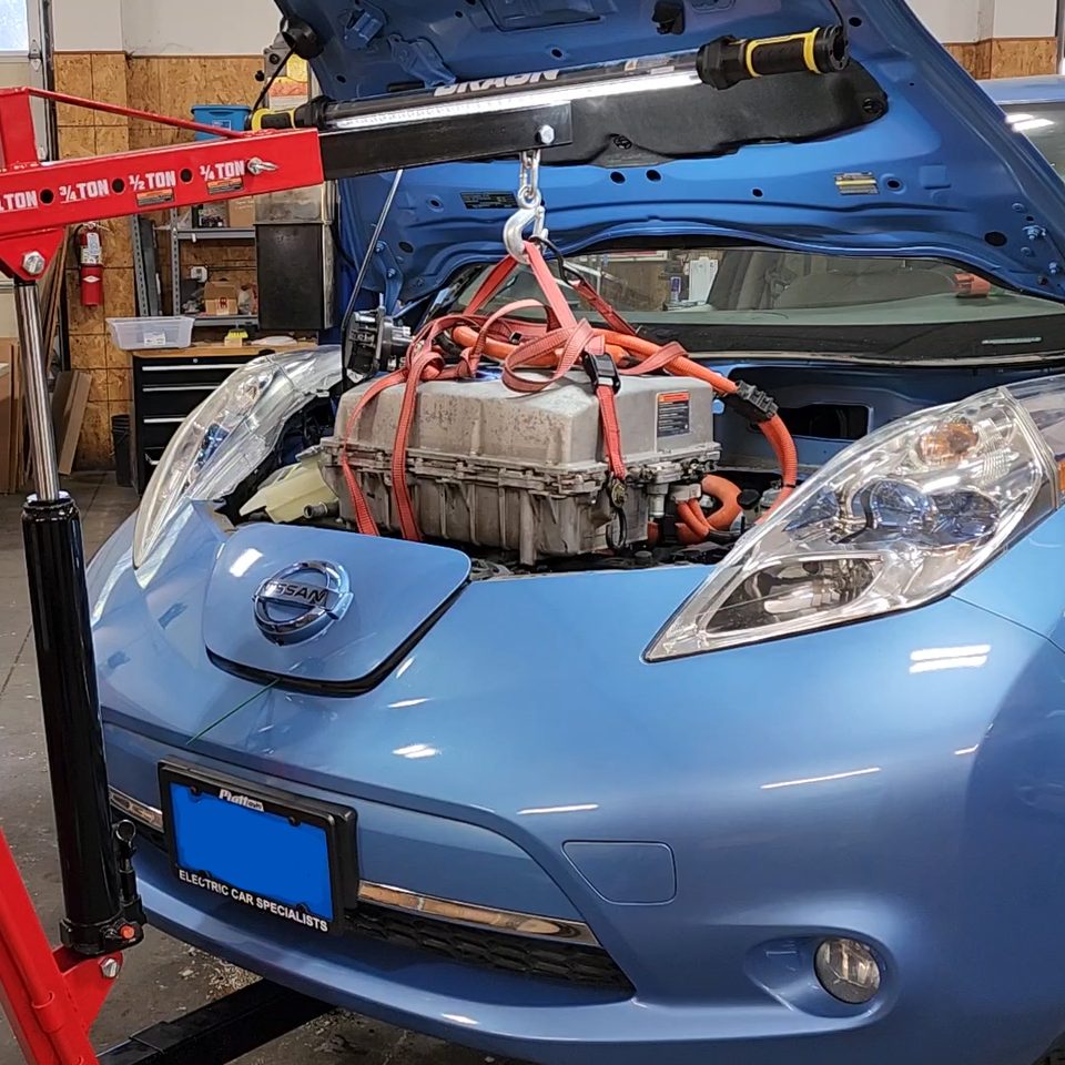 Nissan Leaf with a high-voltage component being lifted from the front bay
