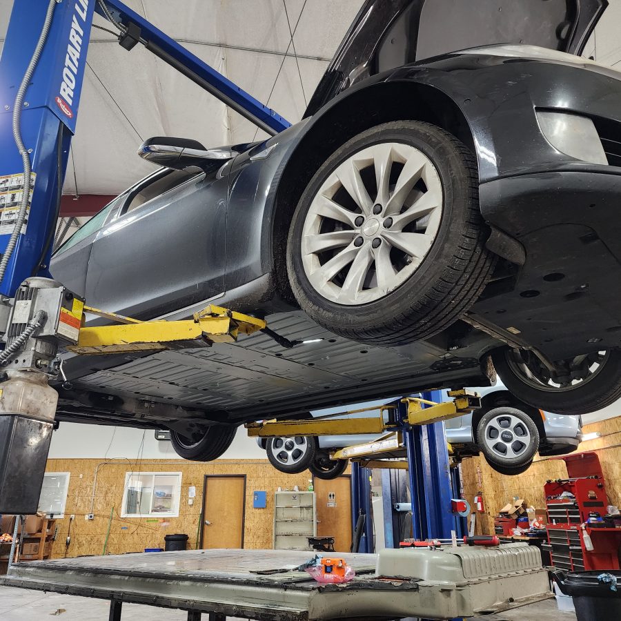 EV on a two-post lift with the high-voltage battery lowered in the WattWorks shop